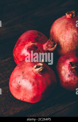 Four ripe pomegranate on rustic wooden table Stock Photo