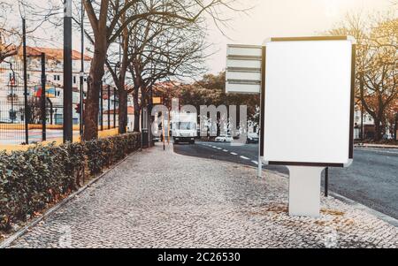 Blank white advert billboard template on a paving stone near the road; empty ad banner placeholder mockup template on the sidewalk; poster mock-up Stock Photo