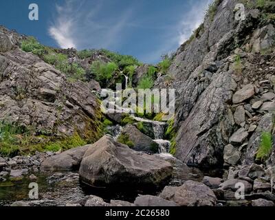 Waterfall from the thawed waters. Melting snow in the hilly tundra. Waterfall Stock Photo