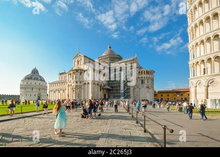 A female tourist poses in front of the Leaning Tower of Pisa with the Cathedral and Baptistery in view, Square of Miracles in Pisa, Italy. Stock Photo