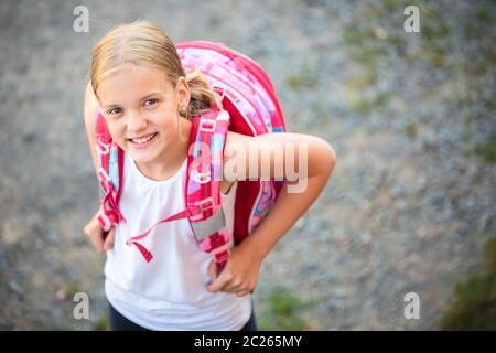 Cute little girl going home from school, looking up with a smile Stock Photo