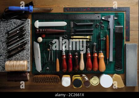 flat lay of leather working tools on wooden desk Stock Photo