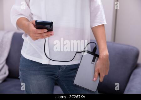 Mid-section Of Woman Using External Hard Disk For Data Transfer Stock Photo