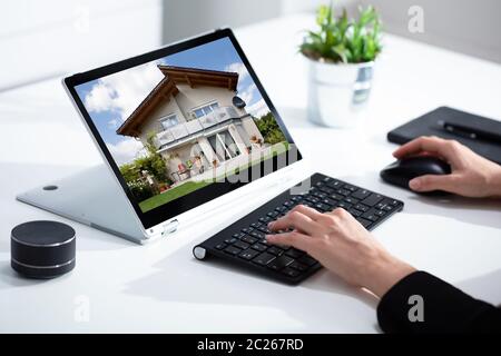 Close-up of businesswoman's hand checking house on laptop Stock Photo