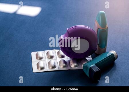 Set of asthma inhaler, accuhaler and anti-allergy pills for treatment asthma. Asthma controller, reliever equipment on dark blue background. Bronchodi Stock Photo