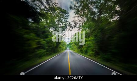 Empty asphalt road and speed motion blur on highway in summer with green trees forest at countryside Stock Photo