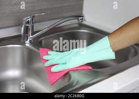 Hands in protective gloves with rag wiping sink. Maid or housewife cleans house. General cleaning or regular wash up. Stock Photo