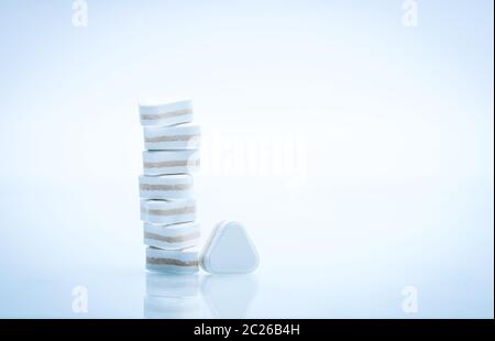 Macro shot of triangle shape tablet pills. Three layers tablet pills for indication antacid, digestive and gastric pain. Group of sandwich tablets pil Stock Photo