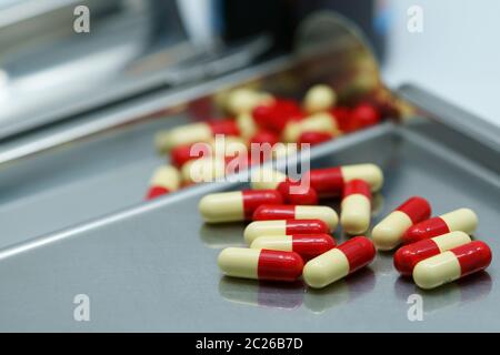 Red-yellow antibiotic capsule pills on  stainless steel drug tray. Antimicrobial drug resistance. Pharmacy background. Pharmaceutical industry. Painki Stock Photo