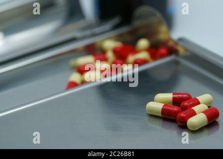 Red-yellow antibiotic capsule pills on  stainless steel drug tray. Antimicrobial drug resistance. Pharmacy background. Pharmaceutical industry. Painki Stock Photo