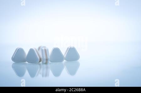 Macro shot of triangle shape tablet pills. Three layers tablet pills for indication antacid, digestive and gastric pain. Group of sandwich tablets pil Stock Photo