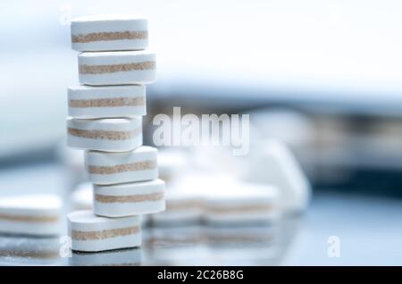 Macro shot of triangle shape tablet pills. Three layers tablet pills for indication antacid, digestive and gastric pain. Group of sandwich tablets pil Stock Photo