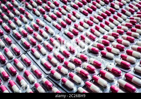 Pink-white antibiotic capsule pills in blister pack. Antibiotics drug resistance. Pharmaceutical packaging industry. Global healthcare. Pharmacy backg Stock Photo