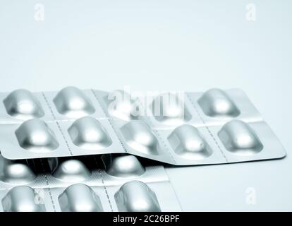 Tablet pills in silver aluminium blister pack packaging on blurred background of pack of pills with copy space Stock Photo
