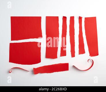 various torn strips of red paper on a white background, flat lay Stock Photo