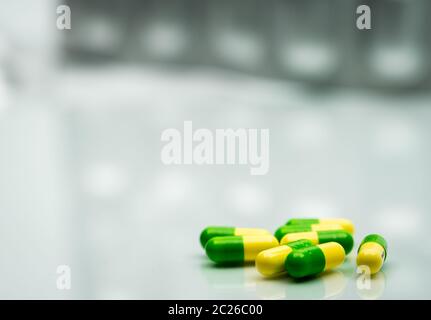 Green, yellow tramadol capsule pills on blurred silver blister pack background with copy space. Cancer pain management. Opioid analgesics. Drug abuse Stock Photo