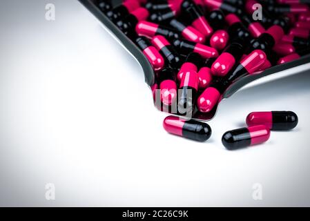 Pink-black capsule pills on drug tray. Antibiotics drug resistance. Global healthcare. Antimicrobial capsule pills. Pharmacy background. Antibiotic dr Stock Photo