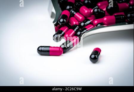 Pink-black capsule pills on drug tray. Antibiotics drug resistance. Global healthcare. Antimicrobial capsule pills. Pharmacy background. Antibiotic dr Stock Photo