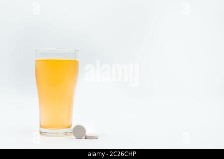 Two effervescent tables on white background and orange effervescent bubbles of calcium and vitamin C effervescent tablets in transparent glass. Vitami Stock Photo