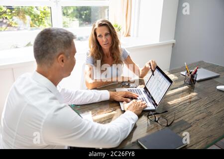 Two Mature Businesspeople Analyzing Gantt Chart On Laptop Over Desk Stock Photo