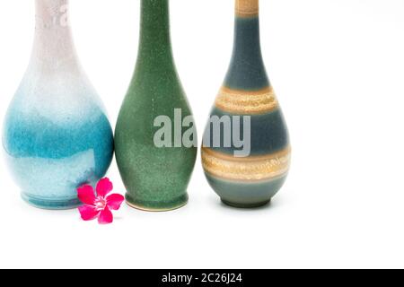 Modern pottery vases with beautiful patterns, pink flower in front of vases isolated on white background Stock Photo
