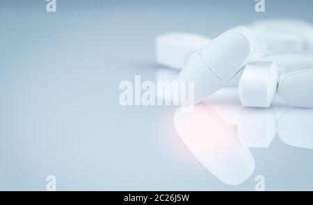 Pile of white oblong tablets pills on gray background. Pharmaceutical industry. Pharmacy products. Painkiller medicine. Calcium tablets. Antibiotic ta Stock Photo