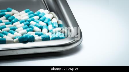 Blue-white capsule pills on stainless steel drug tray. Pharmaceutical industry. Pharmacy background. Antibiotic drug resistance. Global healthcare. Me Stock Photo