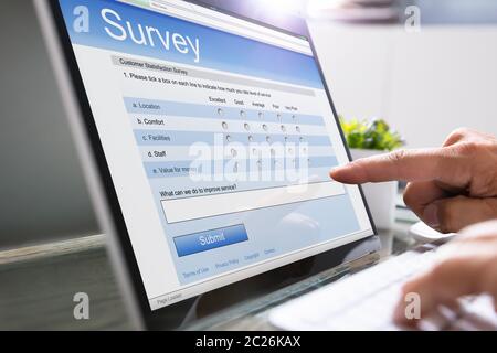 Close-up Of A Businessman Filling Survey On Laptop At Workplace Stock Photo