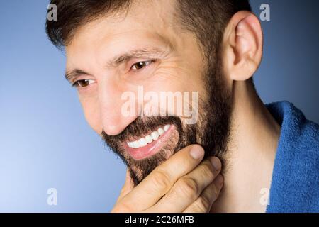 Close-up portrait of smiling middle aged bearded man on blue background. Stock Photo