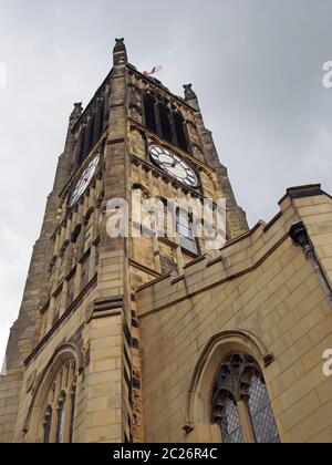 view of the clock tower and building of the historic saint peters parish church in the center of huddersfield against a cloudy s Stock Photo