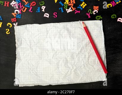 crumpled piece of paper from a school notebook in a cage on a black background, concept back to school Stock Photo