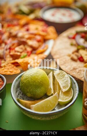 Close up on lime slices in ceramic bowl with various freshly made Mexican foods Stock Photo