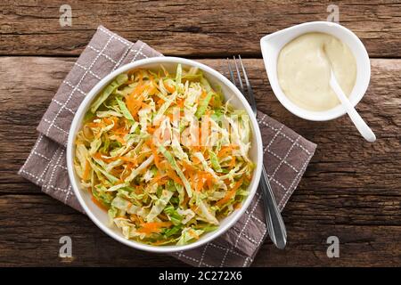 Coleslaw made of freshly shredded white cabbage and grated carrot with homemade mayonnaise-based salad dressing on the side, photographed overhead (Se Stock Photo