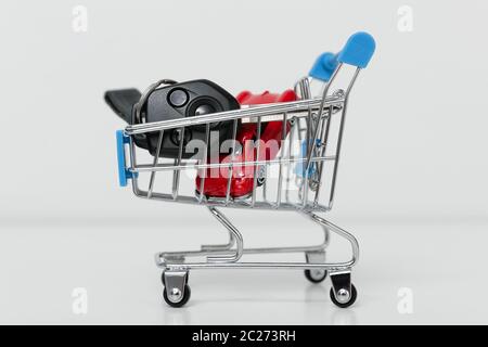 Car purchase concept. Red toy car and car keys in metal shopping cart Stock Photo