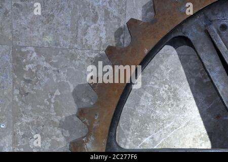 Part of a massive rusty gear on a stone wall background Stock Photo