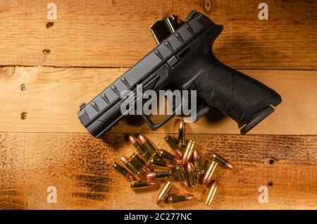 a semi automatic side arm rest on an extra ammunition clip on a wooden surface Stock Photo