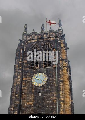 the tower and clock on halifax minster in west yorkshire against a grey cloudy sky with an english flag Stock Photo