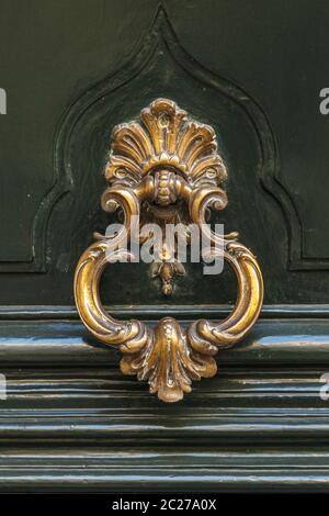 Detail of a bronze metal knocker on a wooden door of house Stock Photo