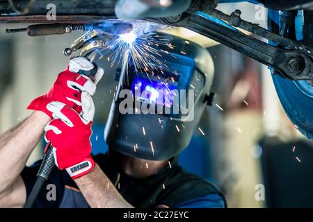 Male in face mask welds with argon-arc welding Stock Photo
