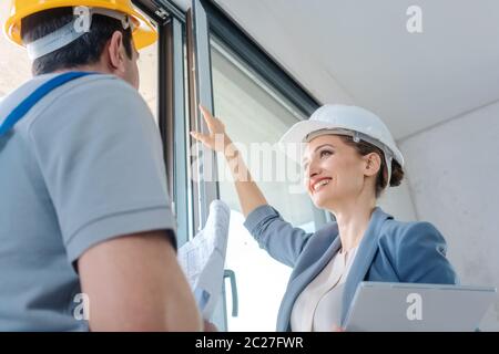 Architect woman and construction worker checking windows on site Stock Photo