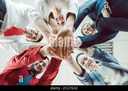 Team of diverse business people stacking their hands together, seen from below Stock Photo