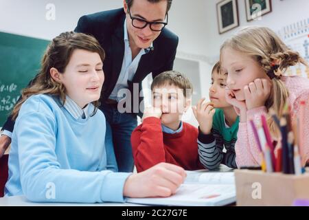 Teacher and students working together in a group or team session being absorbed in their work Stock Photo