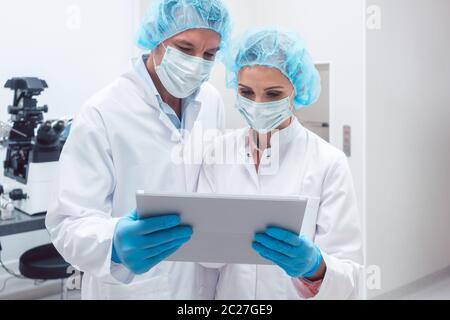 Two scientists working together in lab looking at data on a tablet computer Stock Photo