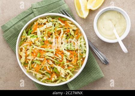 Coleslaw made of freshly shredded white cabbage and grated carrot with homemade mayonnaise-based salad dressing and lemon wedges on the side, photogra Stock Photo