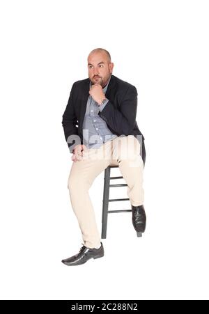 A puzzled middle age business man sitting on a chair with his hand on his chin, looking for a solution for his problem, isolated for white background Stock Photo