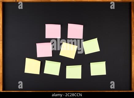 empty square multi-colored stickers hang on a black board in a wooden frame, business concept Stock Photo