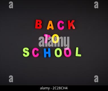 inscription back to school from multi-colored plastic letters on black chalk board, concept back to school Stock Photo