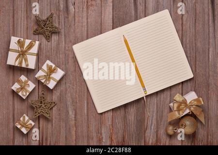 Wooden vintage background with blank sheets in diary, gift boxes and Christmas ornaments. Top view with copy space. New Year and Christmas,  For greet Stock Photo
