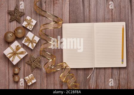Wooden vintage background with blank sheets in diary, gift boxes and Christmas ornaments. Top view with copy space. New Year and Christmas,  For greet Stock Photo