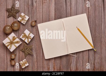 Wooden vintage background with blank sheets in diary, gift boxes and Christmas ornaments. Top view with copy space. New Year and Christmas,  For greet Stock Photo